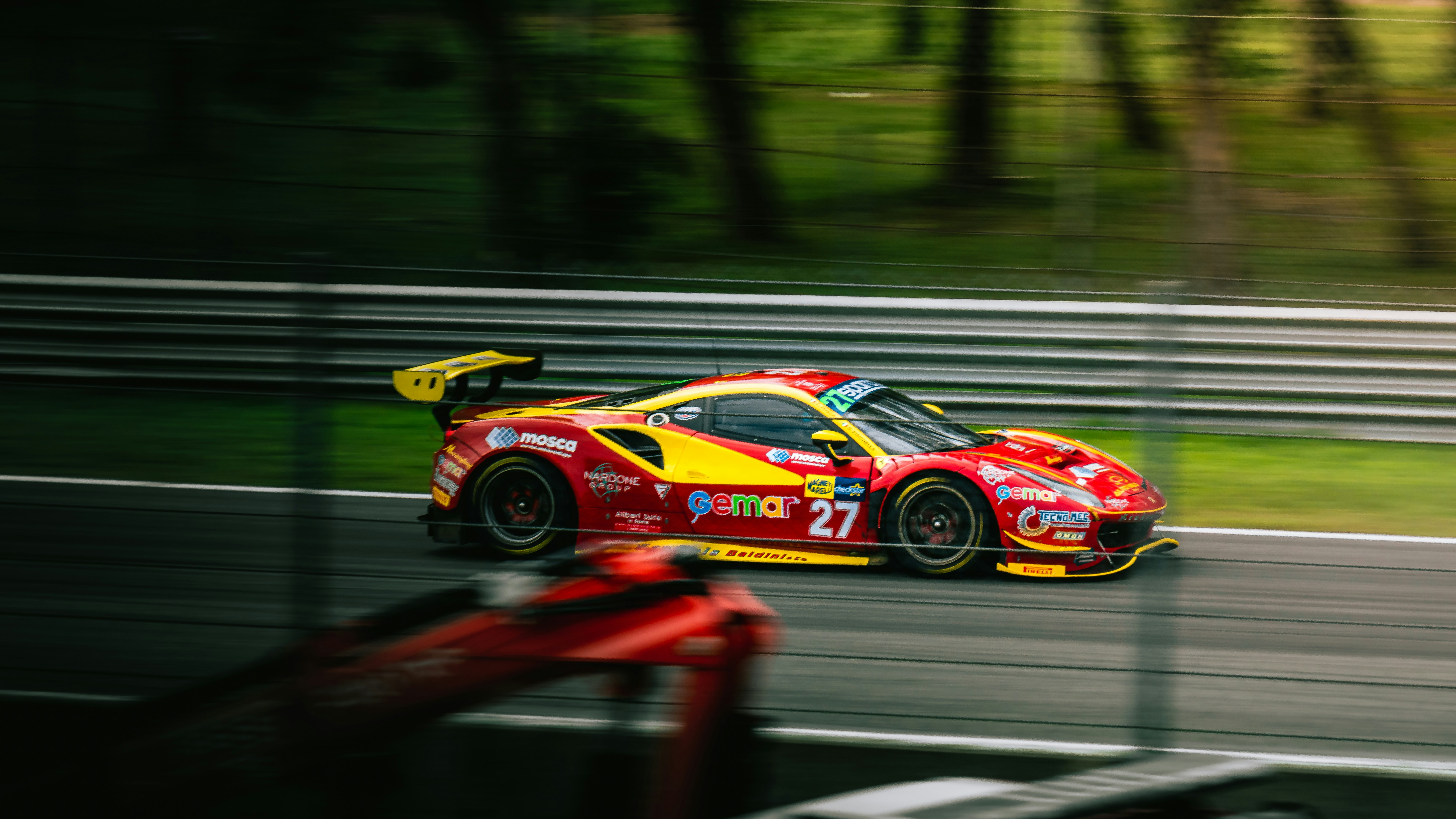 a red and yellow race car driving down a race track, 