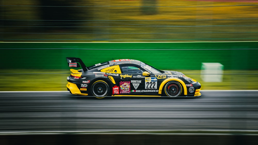 a yellow and black car driving down a race track