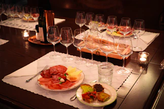 A warmly lit rustic table set with wine glasses and empanadas, inviting guests to a traditional Salta evening.