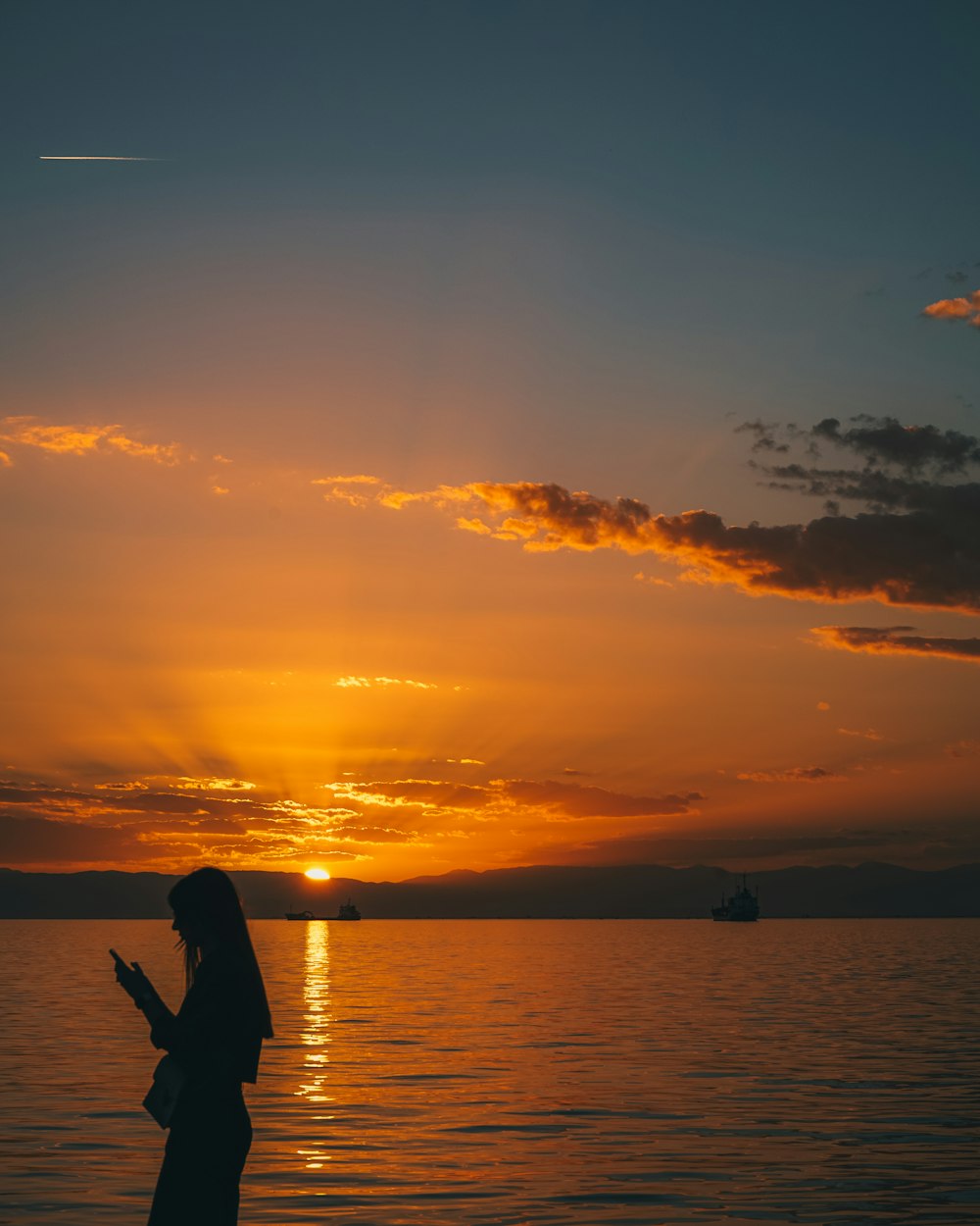 a woman standing in the water at sunset