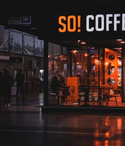 A warm Dunkin' Donuts store front with customers enjoying coffee on a sunny morning.