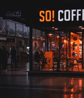 Cozy café interior with warm lighting and guests enjoying coffee.