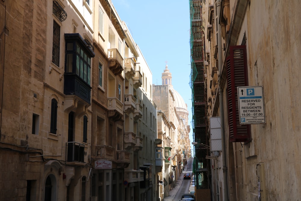 a narrow city street with a church steeple in the background