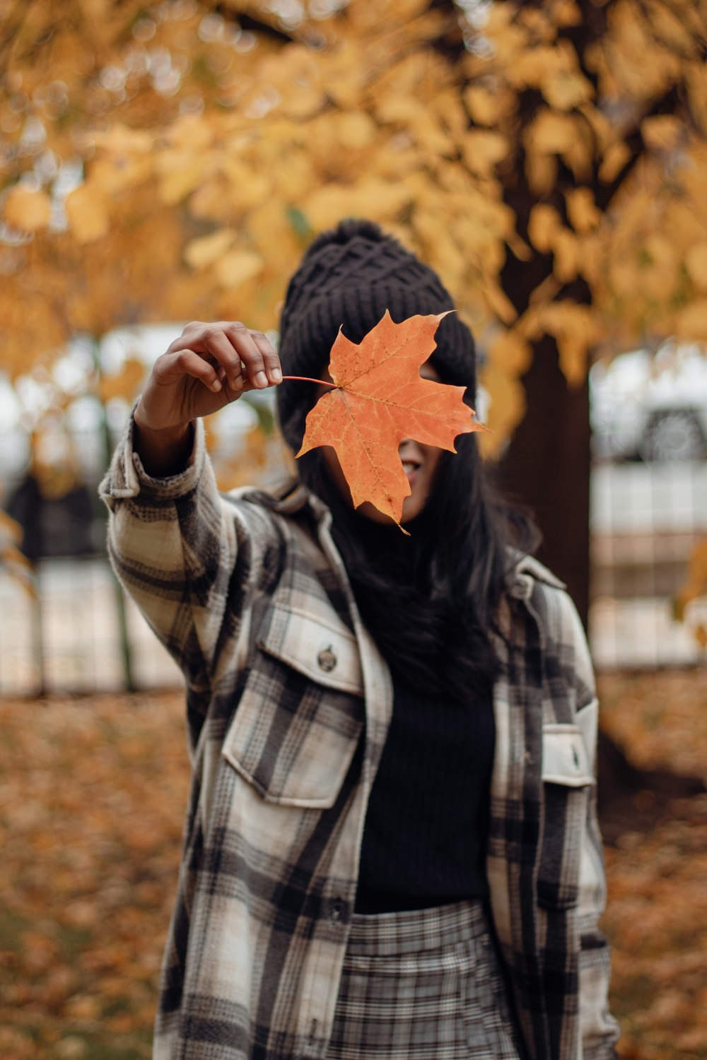 a woman holding a maple leaf in front of her face