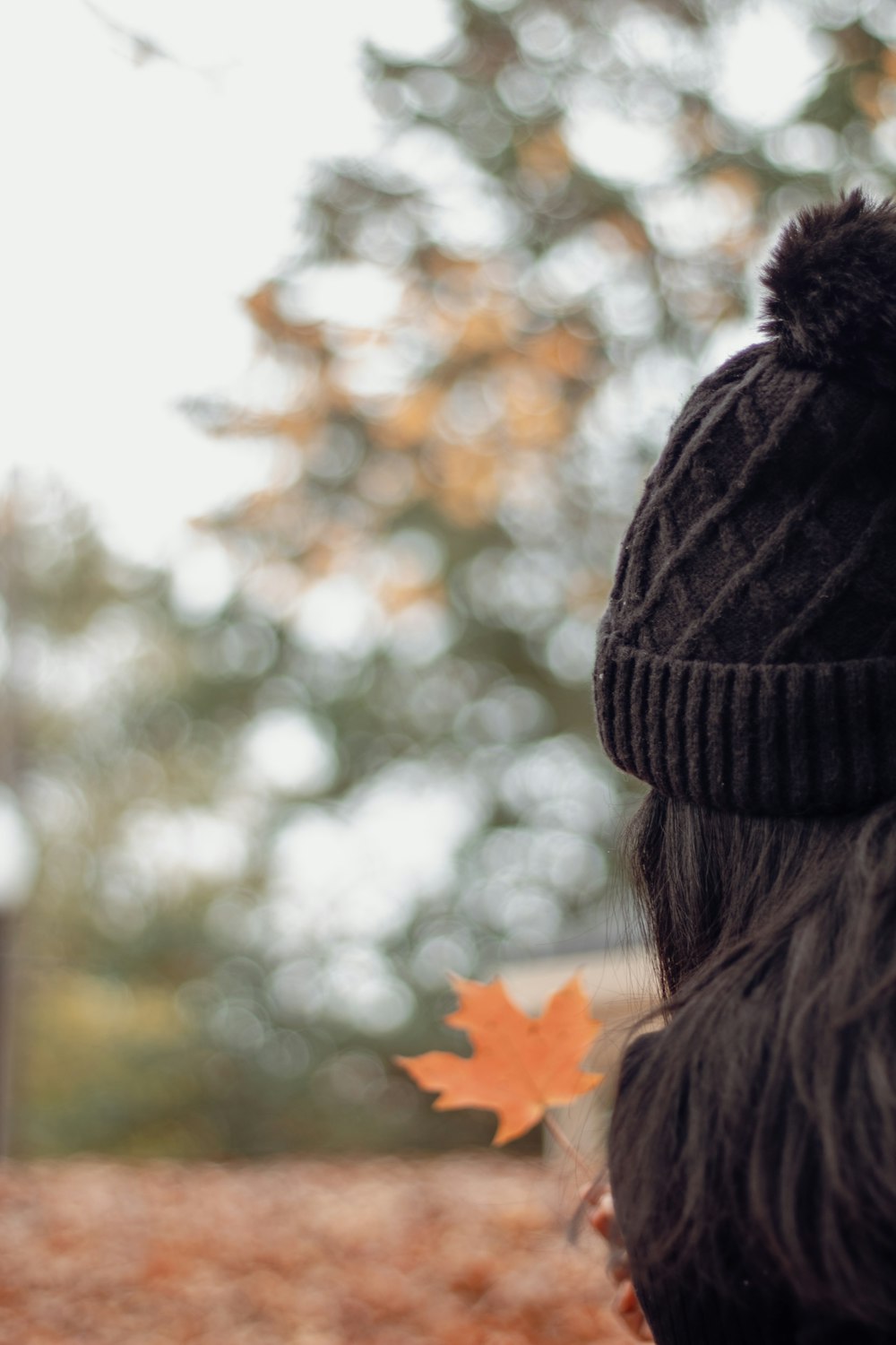 a woman wearing a black hat with a black pom pom