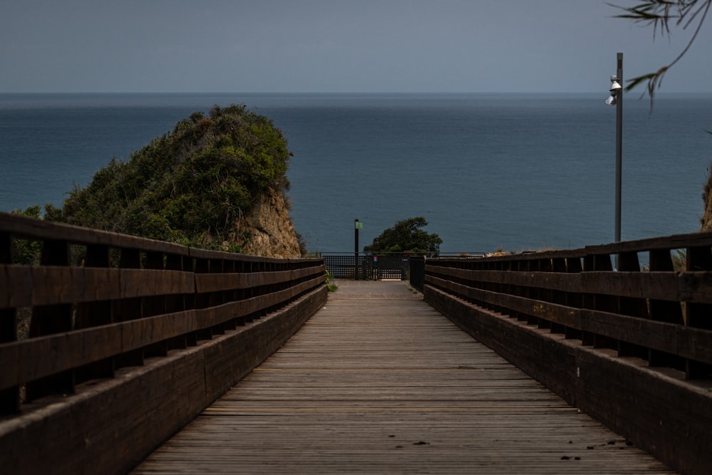 a wooden walkway leading to the ocean on a cloudy day