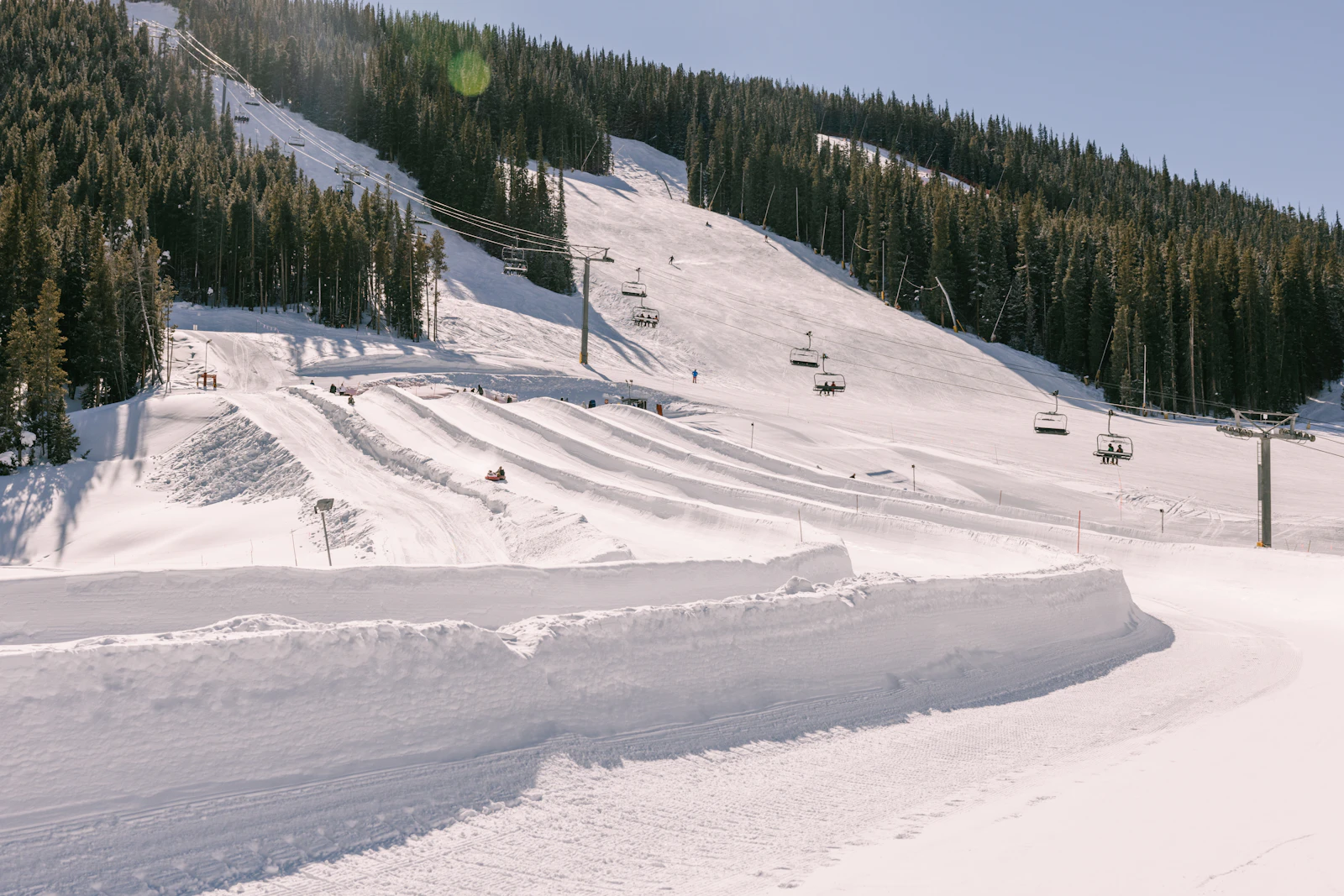 A groomed ski run and chairlift on a sunny day at a Colorado resort