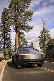 The Cybertruck carefully carrying a classic car on the deck trailer along a scenic highway.