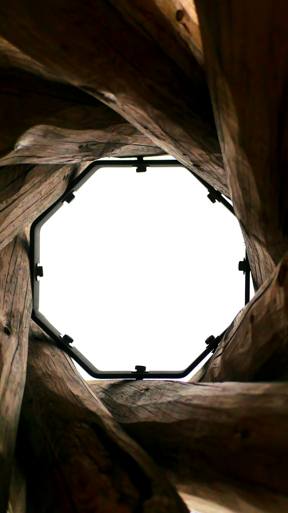 a round hole in a wooden structure with a white sky in the background