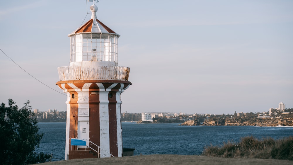 Un faro en una colina con vistas a un cuerpo de agua