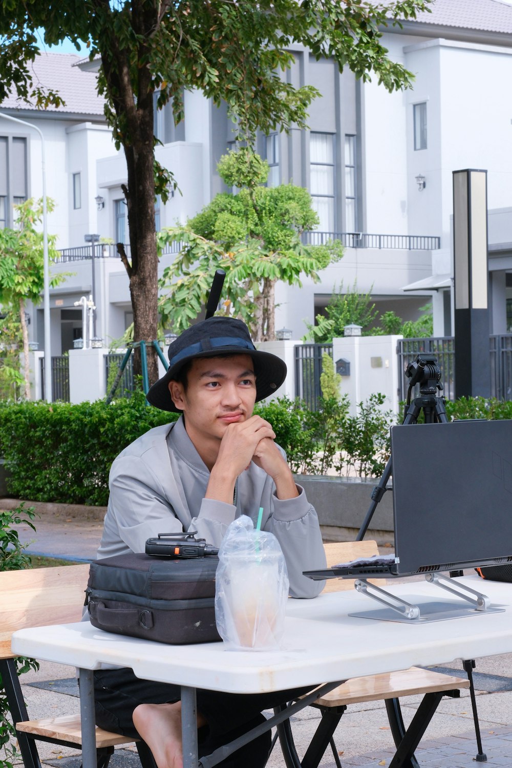 a man in a hat sitting at a table with a laptop