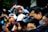 A large crowd of people holding and using cameras and smartphones, eagerly taking photographs of something off-frame. The scene is bustling and lively, with individuals of different ages intently focused on capturing the event. A man in the foreground is using a professional camera, demonstrating the serious interest in photography among the group.
