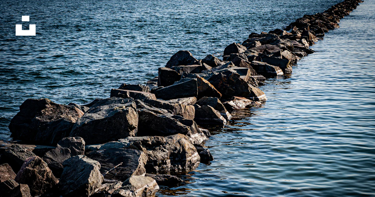 Waterside Rocks A long line of rocks sitting on top of a body of water photo – Free ...