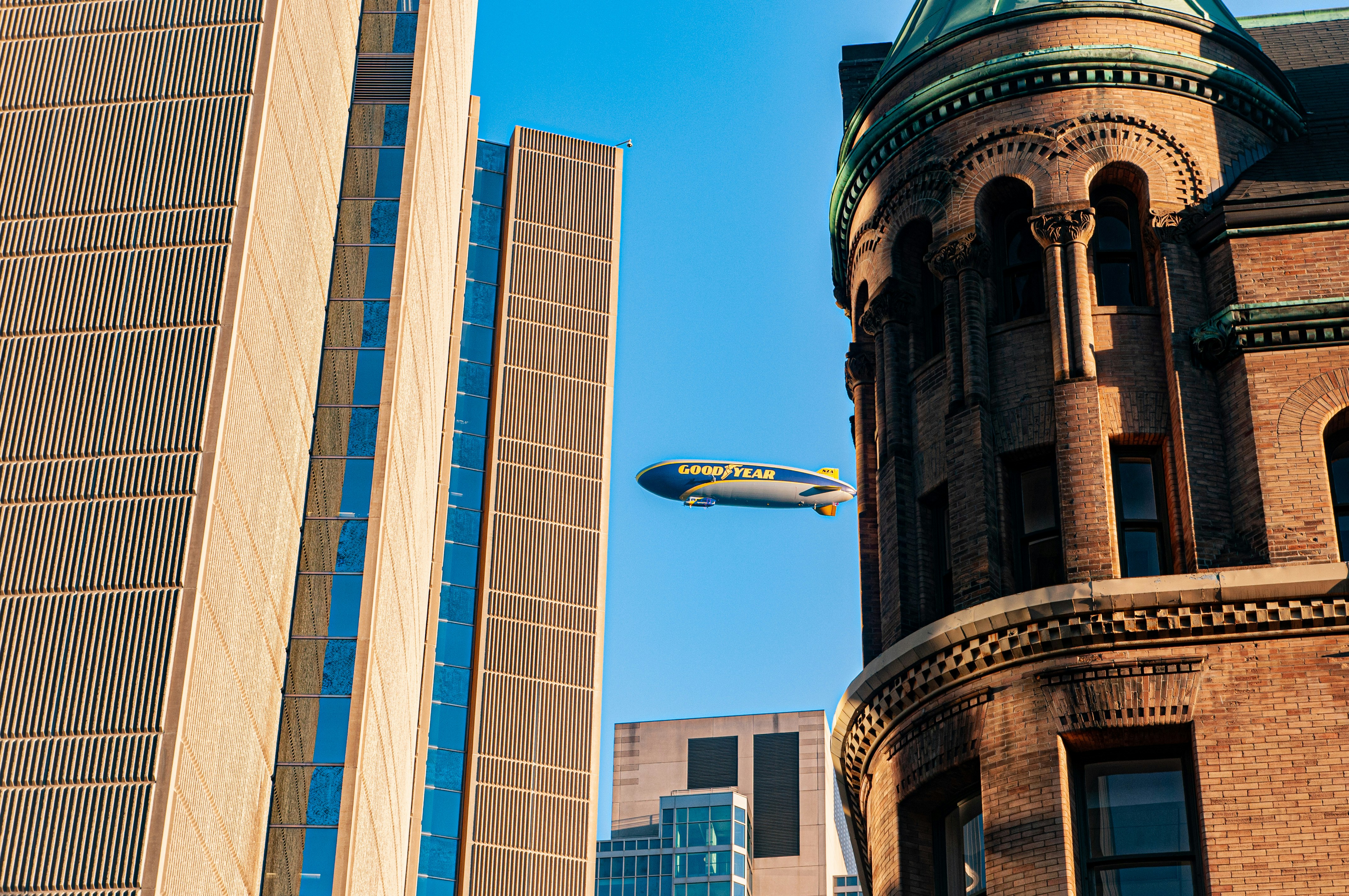 A large airplane flying over a tall building photo – Free Building ...