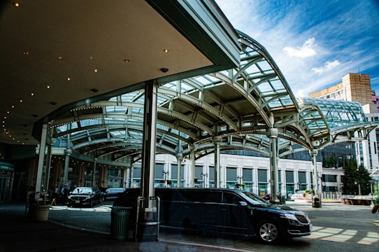 A modern car parking area shaded with sleek lexan canopies under clear blue sky