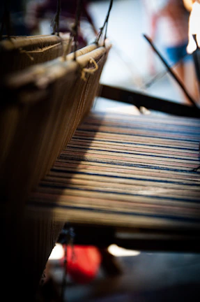 Close-up of artisan hands weaving vibrant threads on a loom with natural light highlighting the textures.