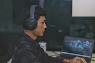 An overhead view of a person using earphones while working on a laptop.
