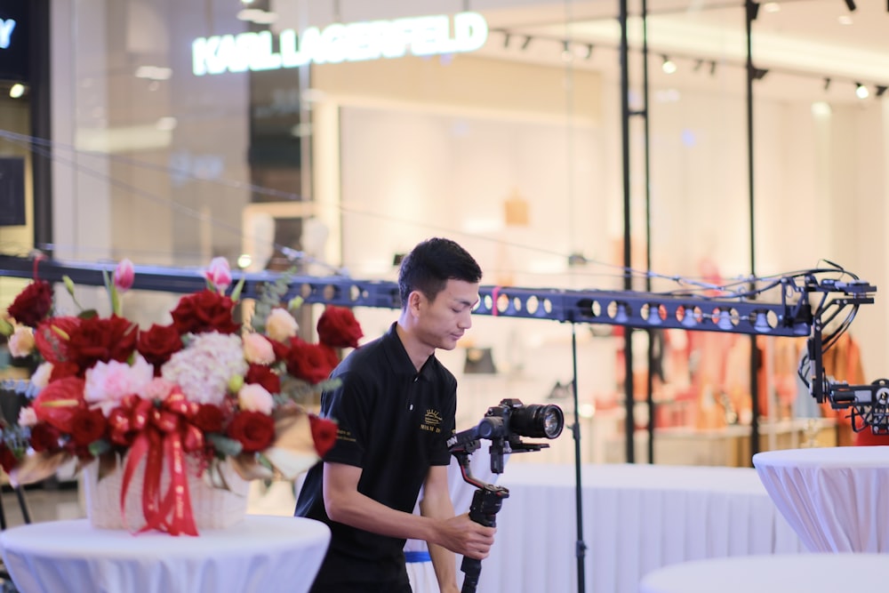 a man holding a video camera in front of a flower display