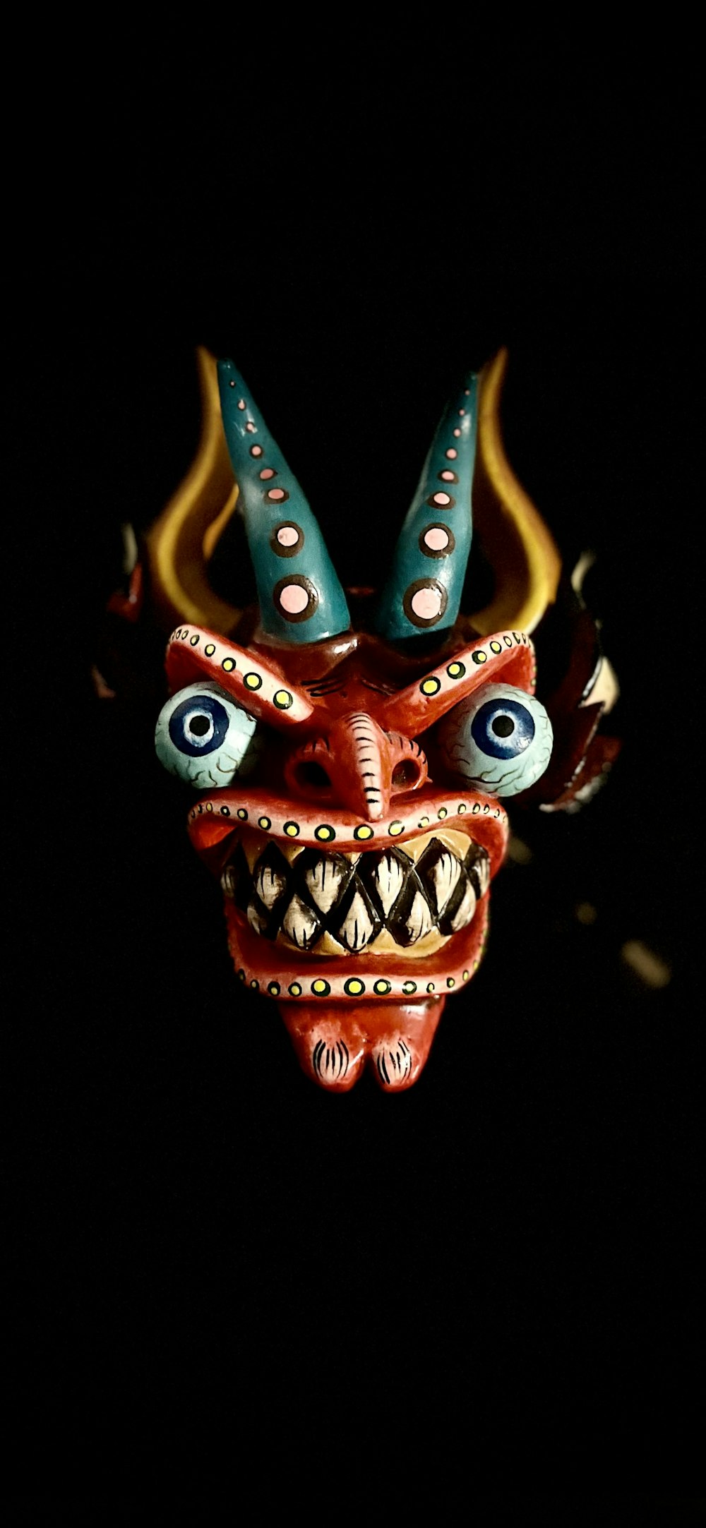 a demon mask with horns and blue eyes