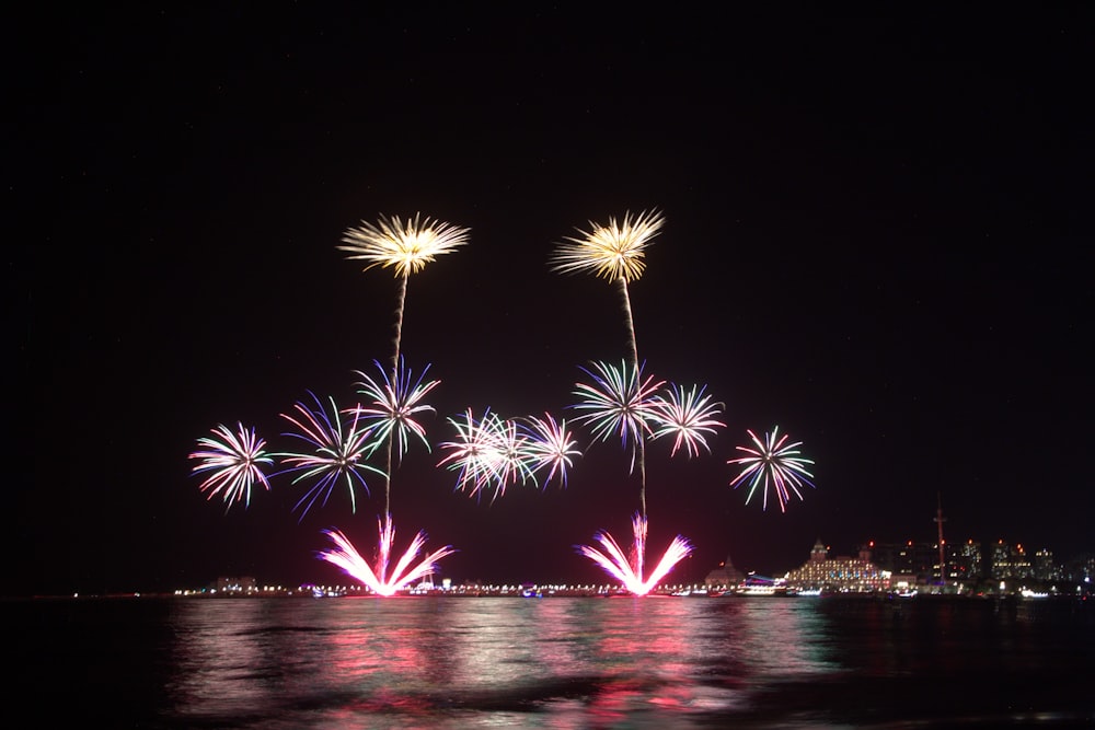 fireworks are lit up in the night sky over a body of water