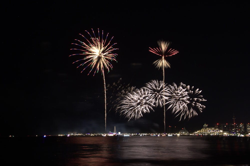 fireworks are lit up in the night sky over a body of water