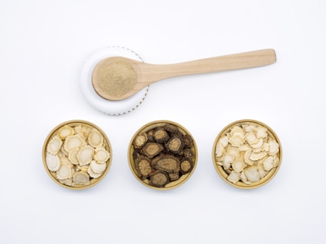 A close-up of natural vitamin supplements in wooden bowls surrounded by fresh herbs
