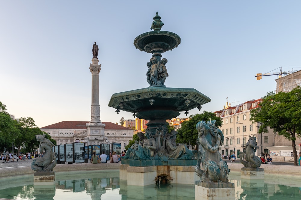a water fountain with statues around it in a city square