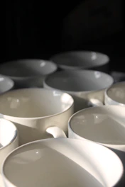 Soft off-white ceramic mugs arranged neatly on a boutique-style display.