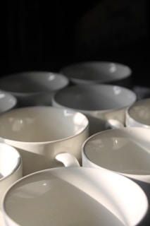 A collection of elegant porcelain mugs arranged on a wooden table.