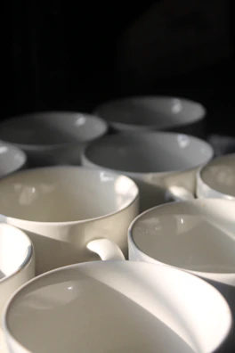 Warm sunlight casting playful shadows on a collection of hand-painted stoneware mugs.