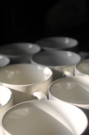 A collection of pink-toned ceramic mugs with subtle textures arranged on a linen cloth.