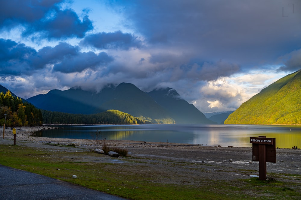 a body of water surrounded by mountains under a cloudy sky