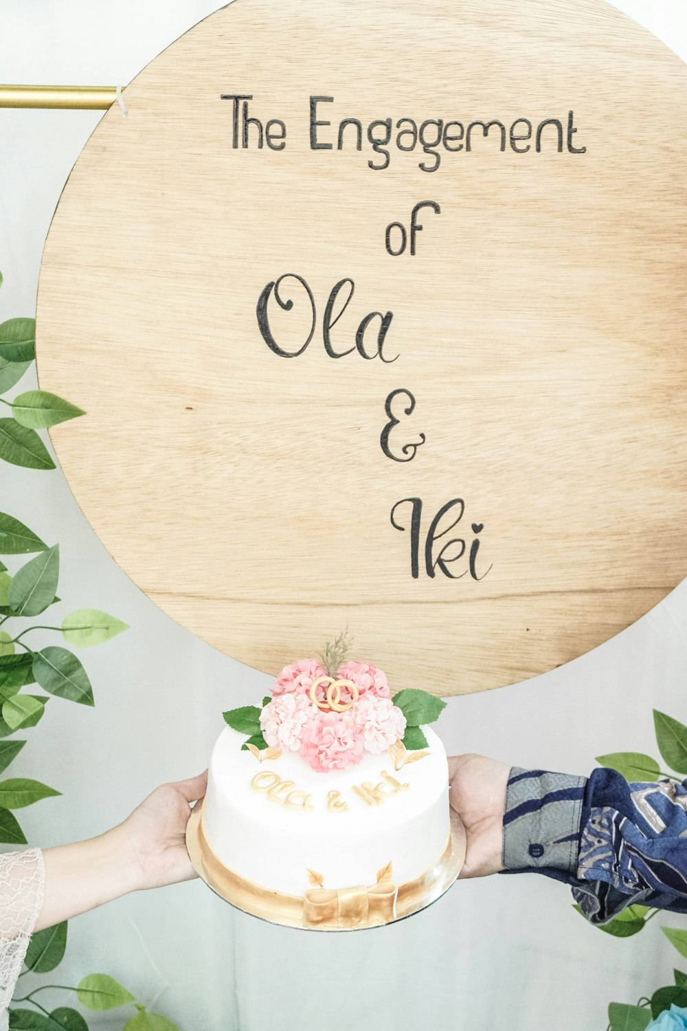 a person holding a cake in front of a wooden sign