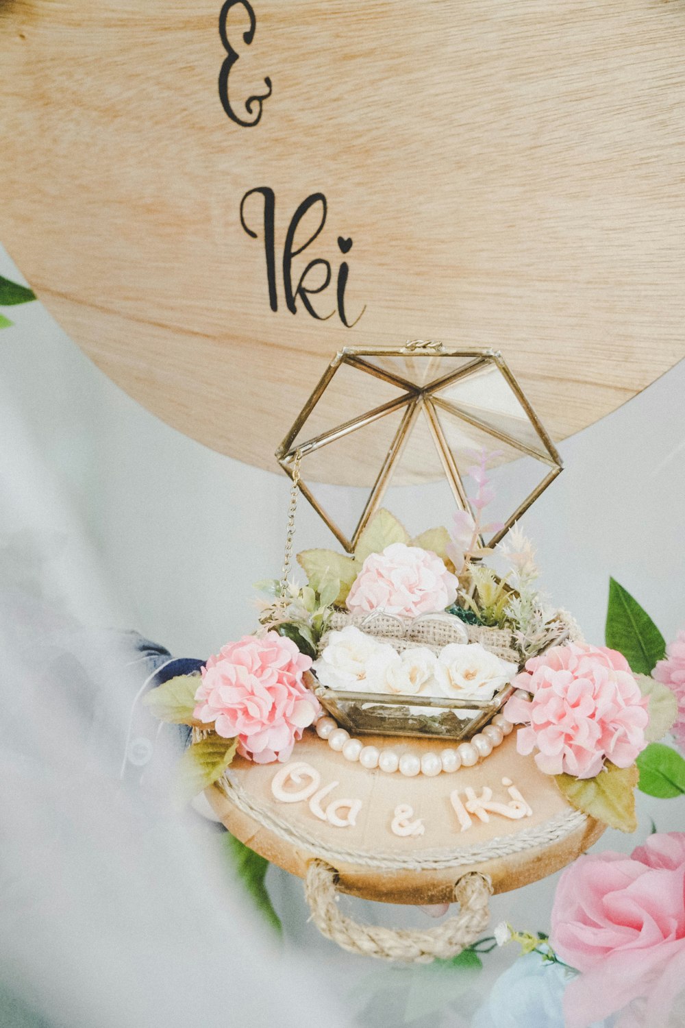 a wooden sign with flowers and a cake on it