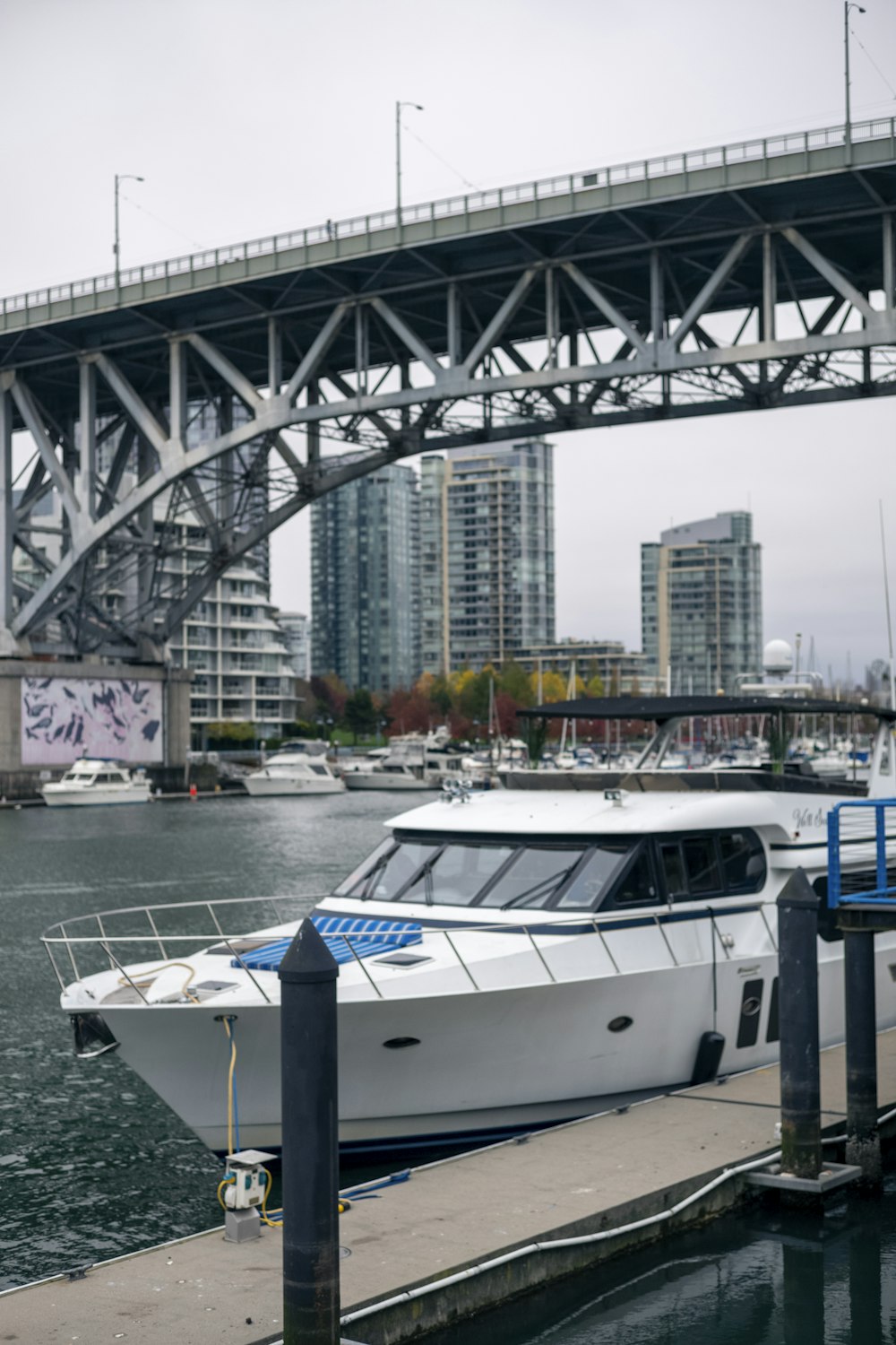 a white boat docked at a dock in front of a bridge