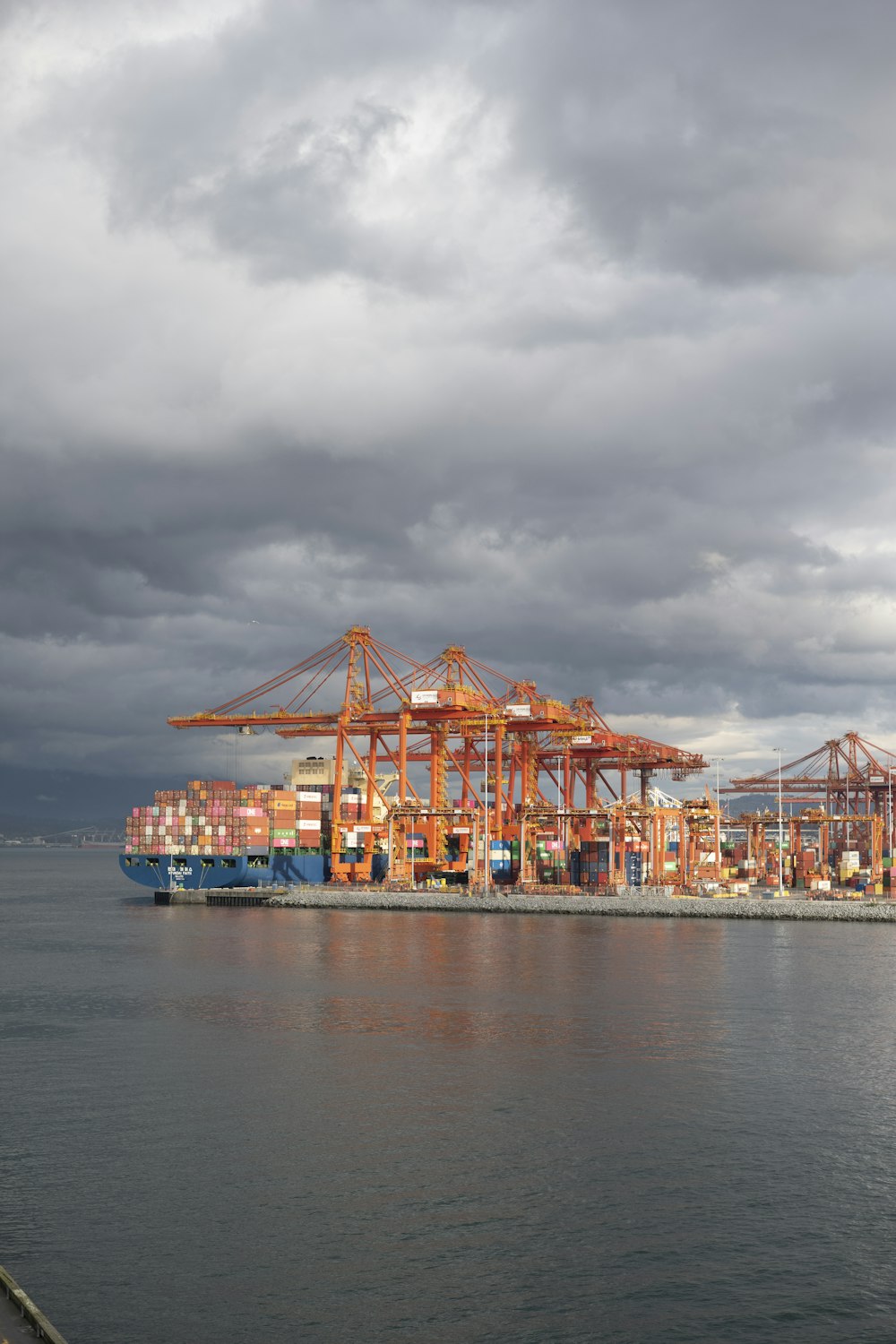 a large cargo ship in the water under a cloudy sky