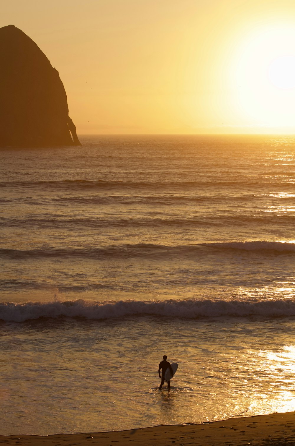 Una persona caminando hacia el océano con una tabla de surf