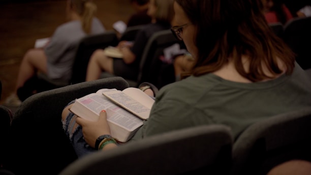 a woman reading a book while sitting in a chair