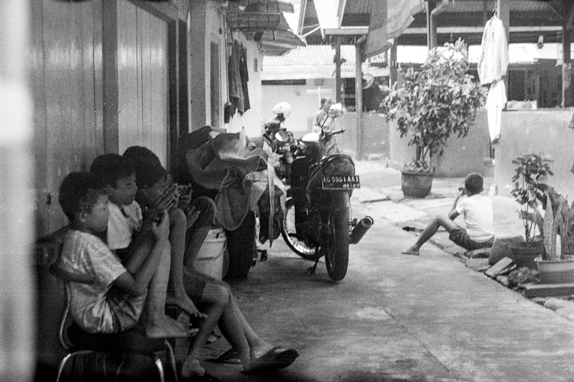 A group of children sitting together on a dusty street in Ibadan, some holding small bowls, capturing the reality of street begging.