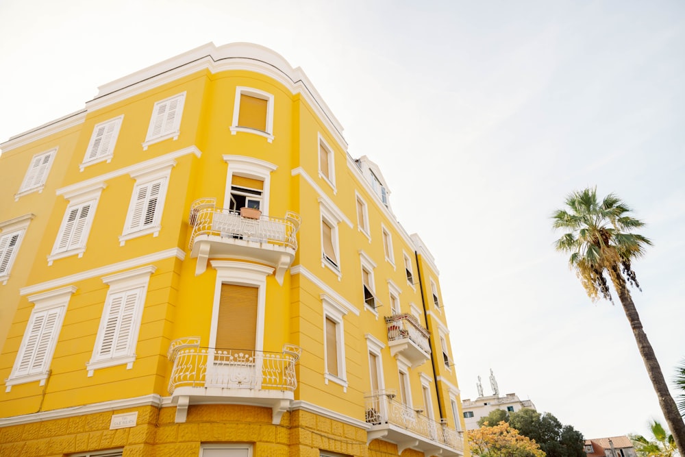 a tall yellow building with white windows and balconies