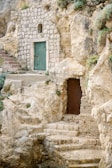 a stone building with a green door and steps