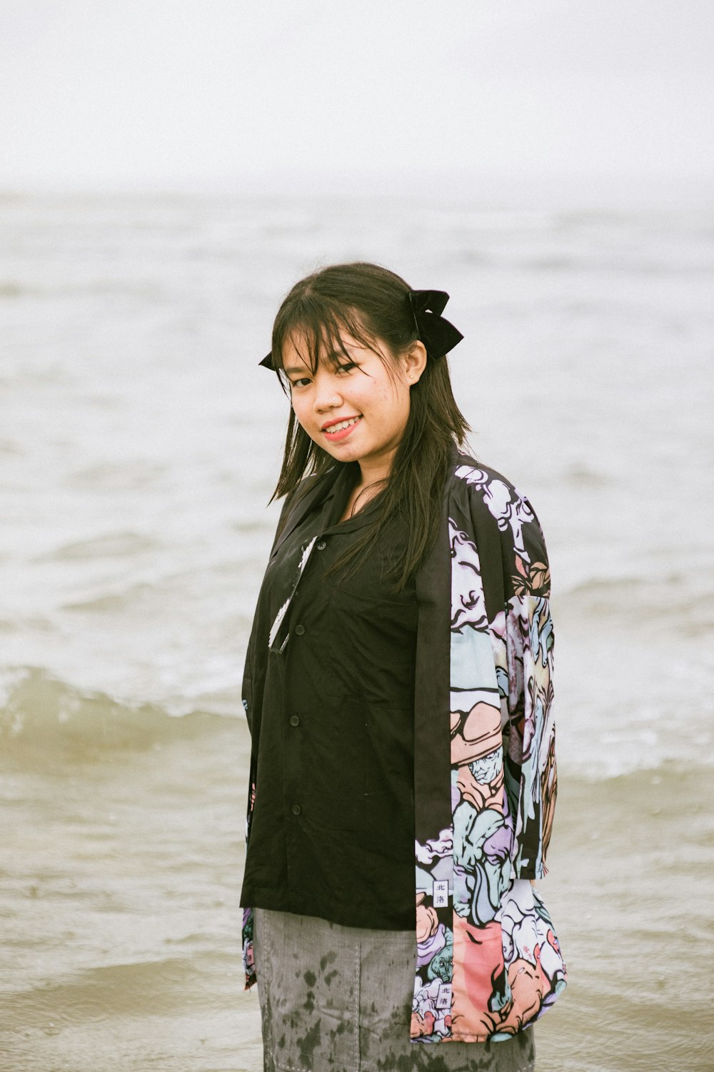 a woman standing in the ocean with her hair in a ponytail