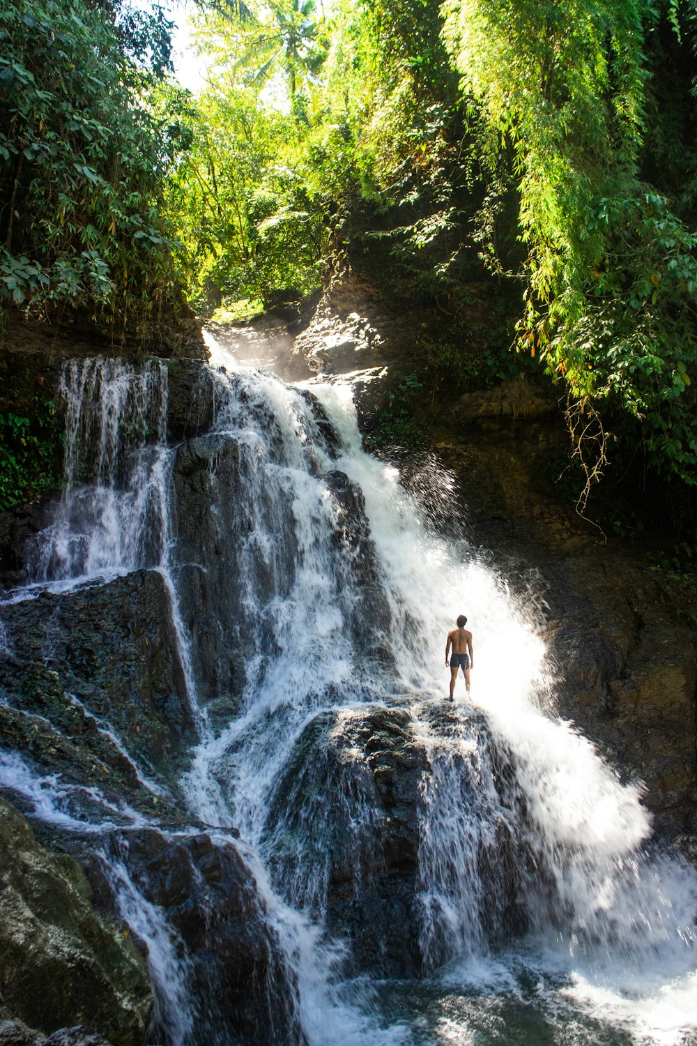 un homme debout sur un rocher devant une cascade