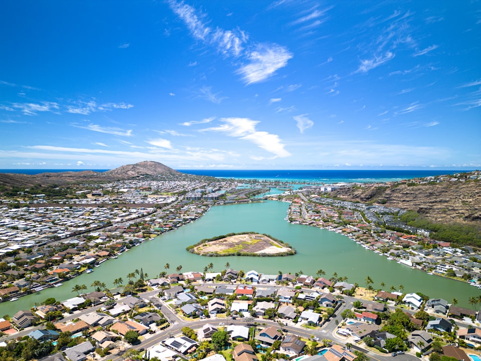 Aerial view of a dense Hawaii contractor license market: single-family homes and a marina neighborhood on Oahu below Koko Head crater and the ocean
