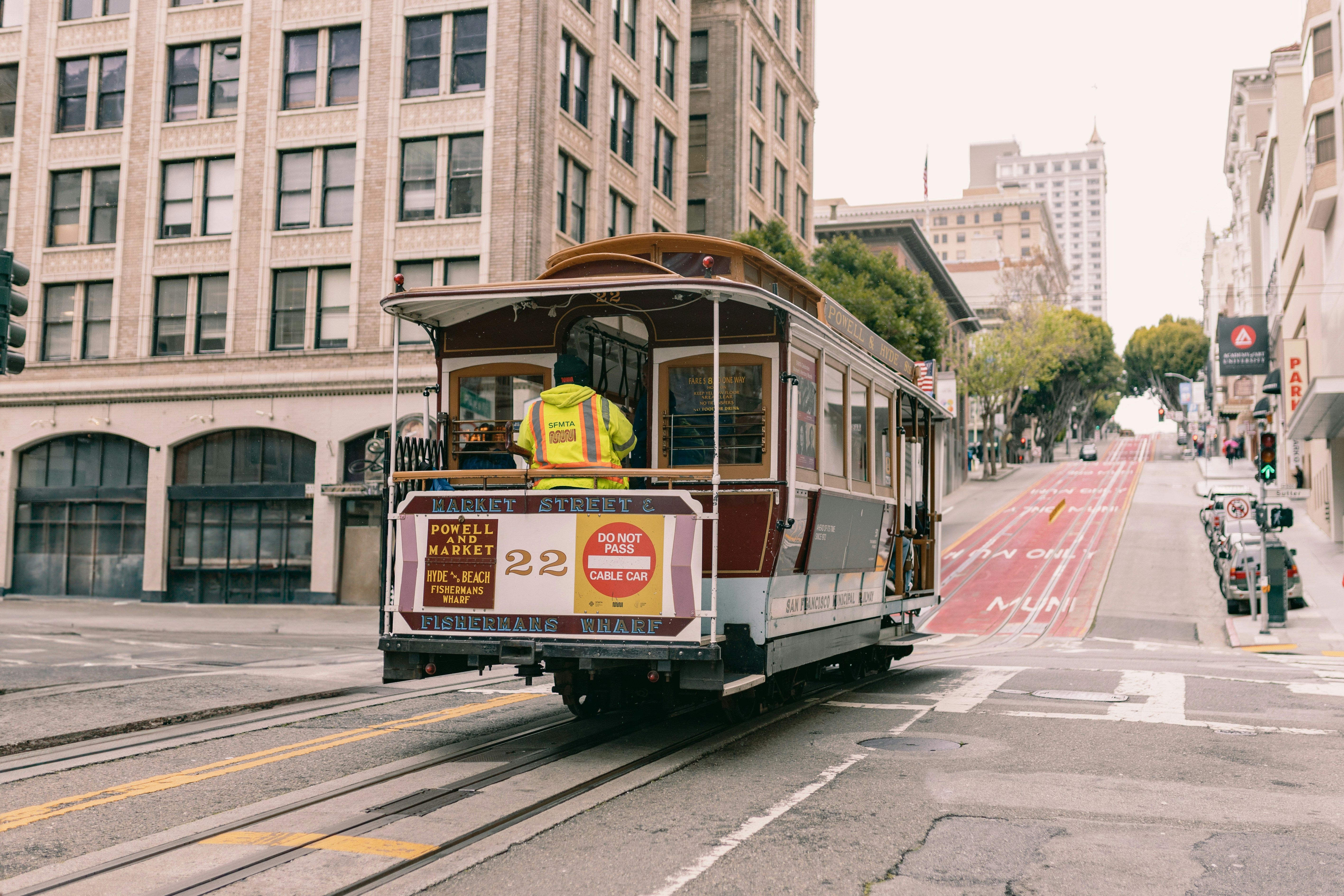 a trolley car traveling down a street next to tall buildings, San Francisco