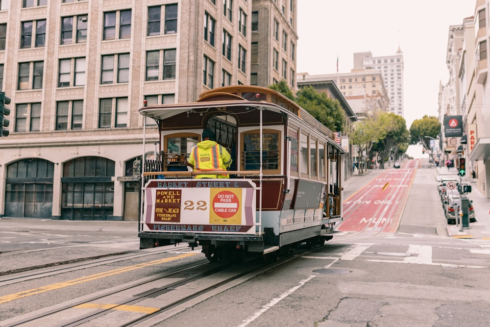 a trolley car traveling down a street next to tall buildings