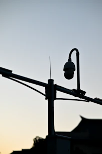 Close-up of a modern security camera capturing a quiet suburban street at dusk.