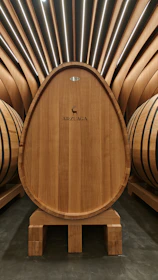 A rustic wooden barrel with the Viña Chouzal label in a minimalist cellar setting.