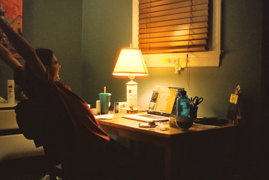 A calm and inviting workspace with a person gently stretching their back near a window.