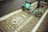 A teal electric scooter is parked on a designated bike parking area marked with white paint symbols and text in both English and Chinese. The ground consists of paved bricks, and the area appears to be part of a street sidewalk.